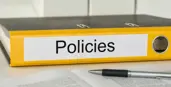 alt="Photo of yellow binder on a table with some paper and a pen in the foreground"