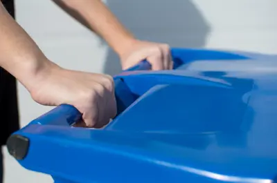 hands on a blue recycling cart