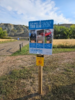 Photo of sign near a boat launch on the South Saskatchewan River in Medicine Hat reminding boaters to Clean, Drain, and Dry their gear to prevent Aquatic Invasive Species