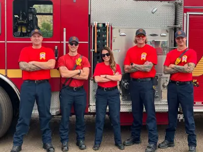 group of fire and emergency services crews standing with arms crossed wearing their red t-shirts