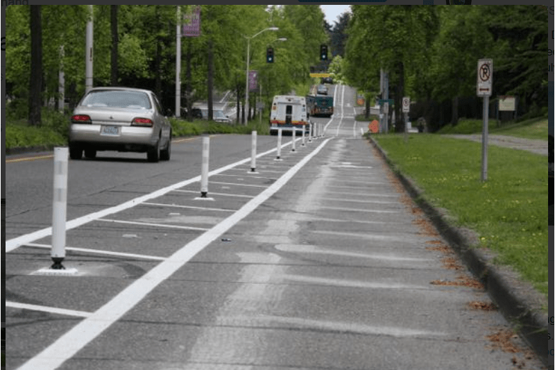 Photo of cars on road with white delineators separating driving area from curb